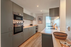 Eine moderne Küche mit grauen Schränken, einem eingebauten Backofen und einer Holzarbeitsplatte.