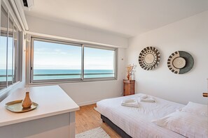 Ein Schlafzimmer mit großem Fenster, einem Bett, einem Nachttisch und zwei Wandplatten.