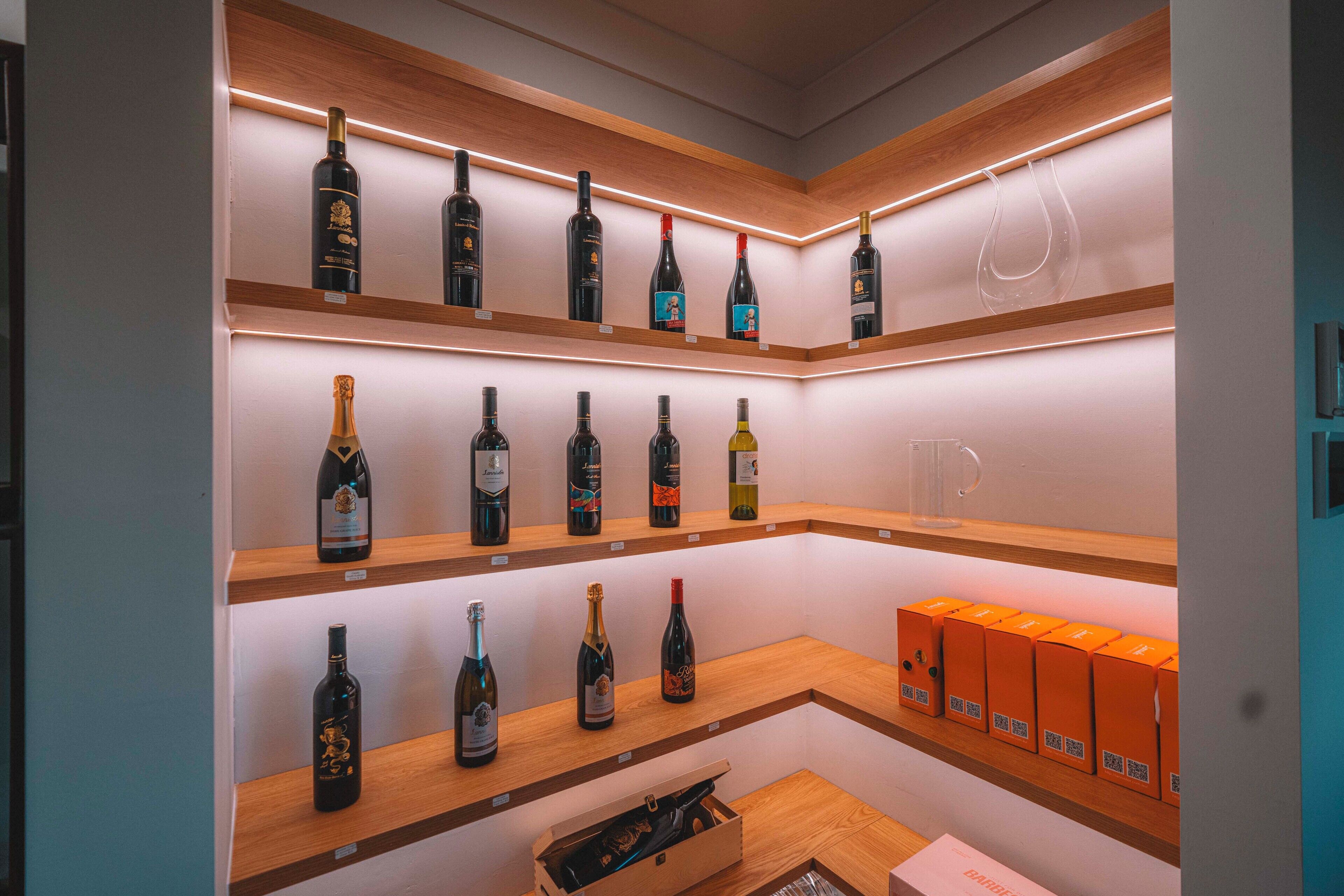 A wine display with bottles on shelves and a box of wine glasses.