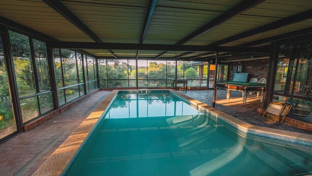 An indoor swimming pool with clear glass walls, a tiled floor, and a wooden ceiling. - Vineyard Retreat in the Heart of McLaren Vale (McLaren Vale)