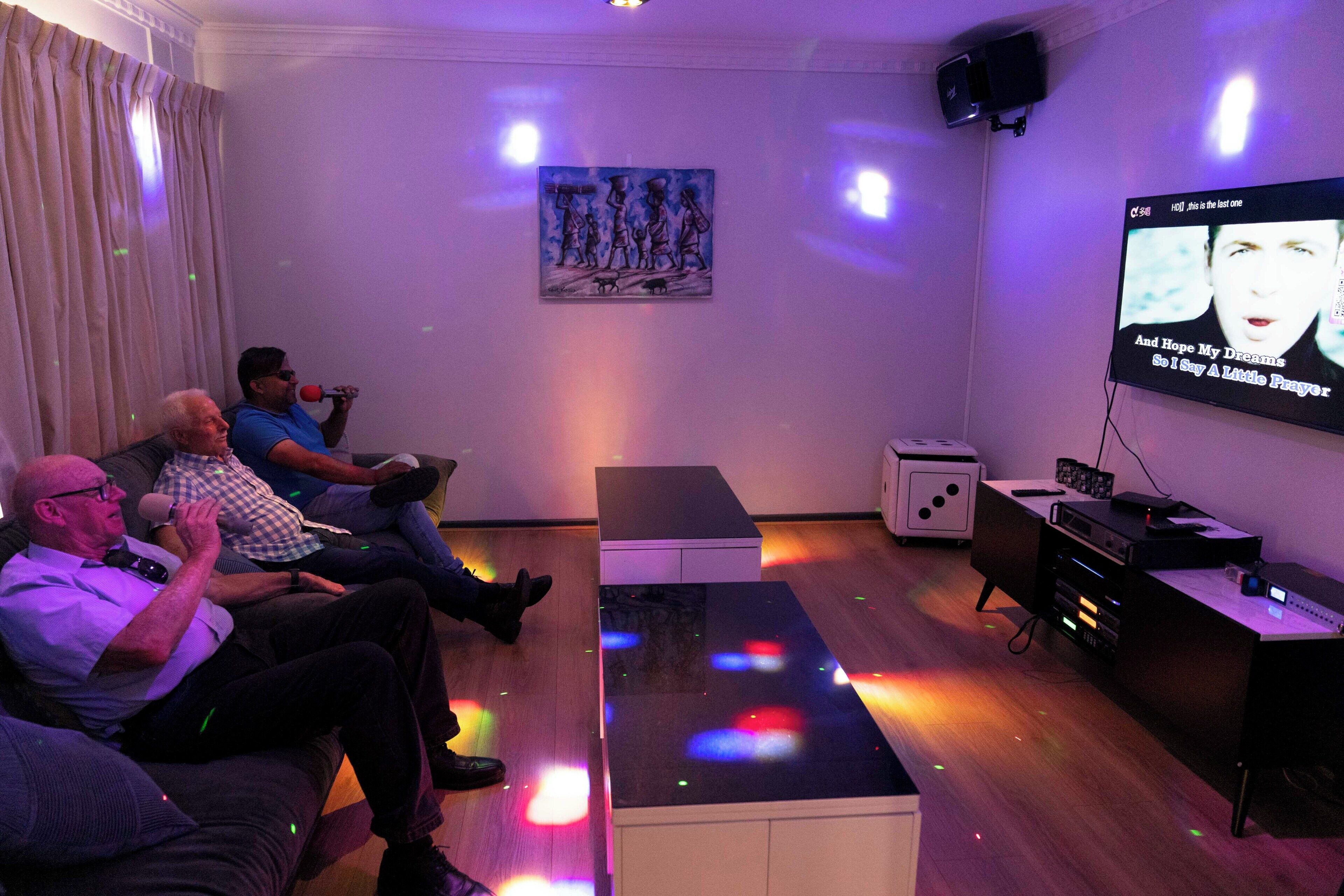A room with a flat-screen TV mounted on the wall, a wooden floor, a white cabinet, and a painting on the wall.
