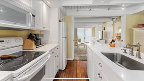 Une cuisine moderne avec des meubles blancs, des appareils en acier inoxydable et un plancher en bois.