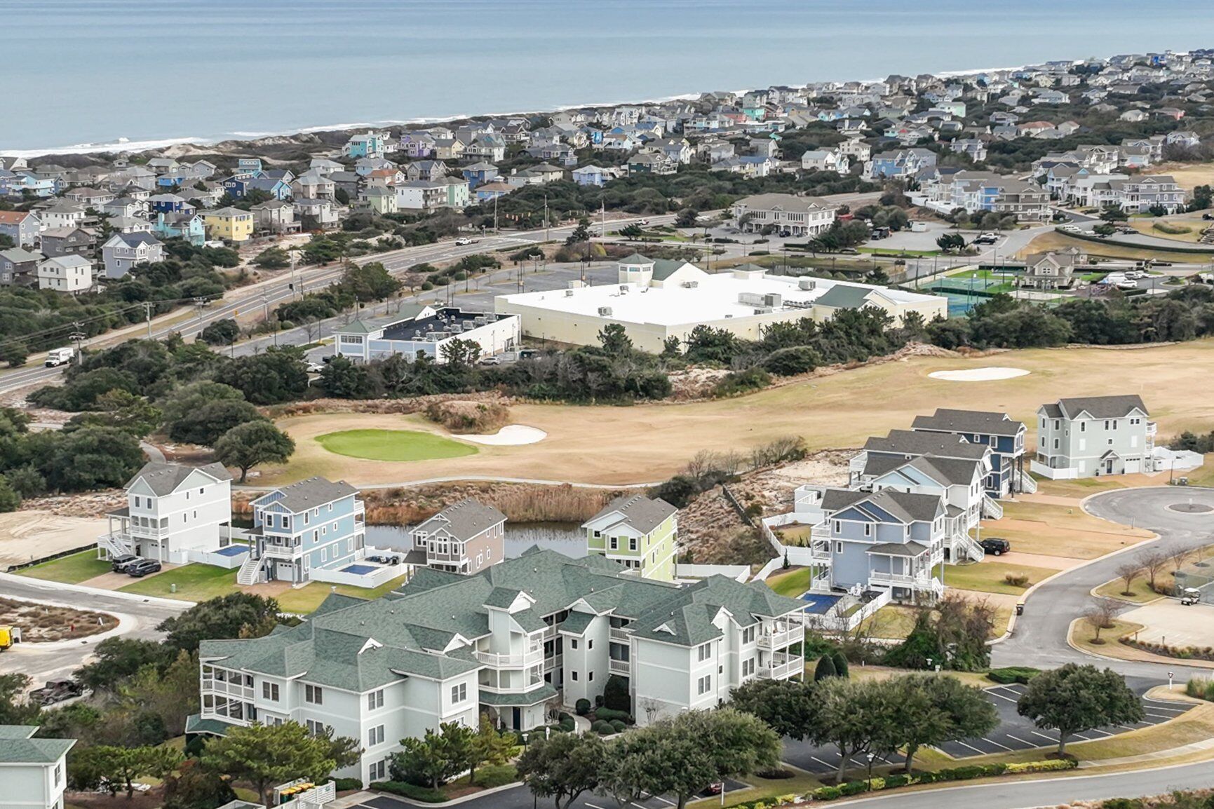 A residential area with houses, a golf course, and a large white building.