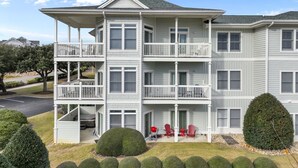 Un immeuble résidentiel à plusieurs étages, doté de balcons, d’un porche avant couvert et d’une pelouse bien entretenue.