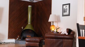 A cozy living room with a wood-burning stove, leather furniture, and a lamp. - Cozy 3-bedroom house in Anchorage (Anchorage)