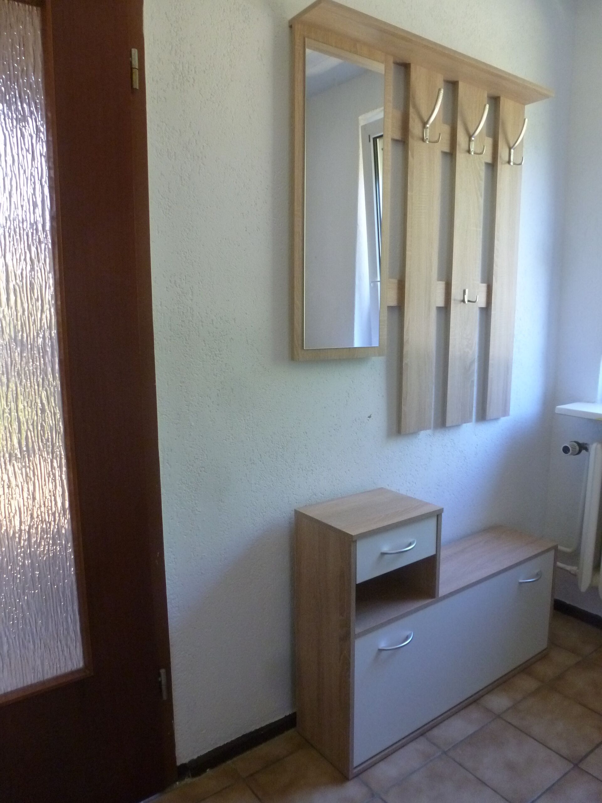 A room with a wooden cabinet, a mirror, and a radiator.