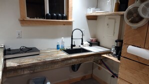 Une cuisine de taille réduite, dotée d’un plan de travail en bois, d’un évier, d’une cuisinière et d’une poubelle.