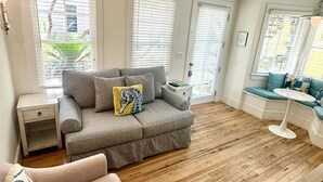 A living room with a grey sofa, a small table, and a wooden floor.