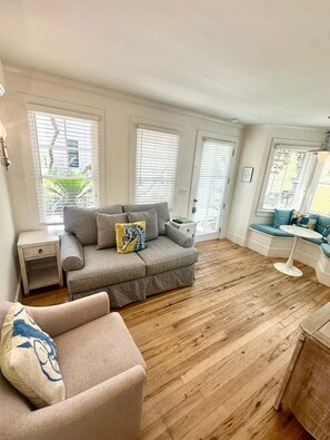 A living room with a grey sofa, a small table, and a wooden floor.