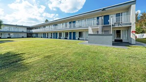 A modern motel with a two-story structure, a central courtyard, and a parking area. - Suburban Studios Daytona Beach - Speedway (Daytona Beach)