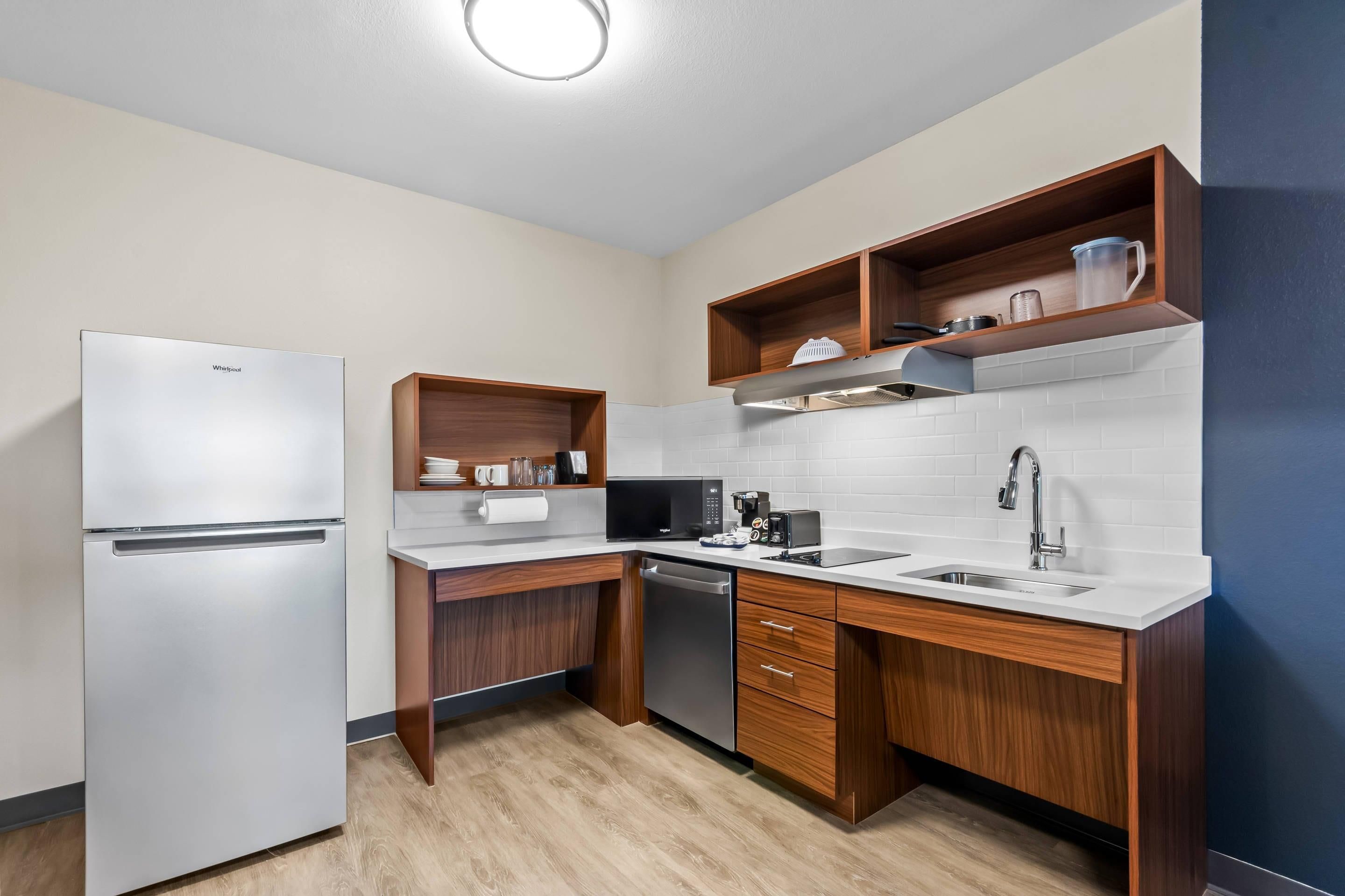Una cocina compacta con refrigerador, microondas, cafetera y lavabo.