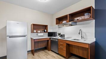Una cocina compacta con refrigerador, microondas, cafetera y lavabo.