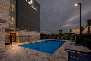 A hotel with a swimming pool, outdoor seating, and a large sign. - Everhome Suites Panama City Beach - 30A (Panama City Beach)