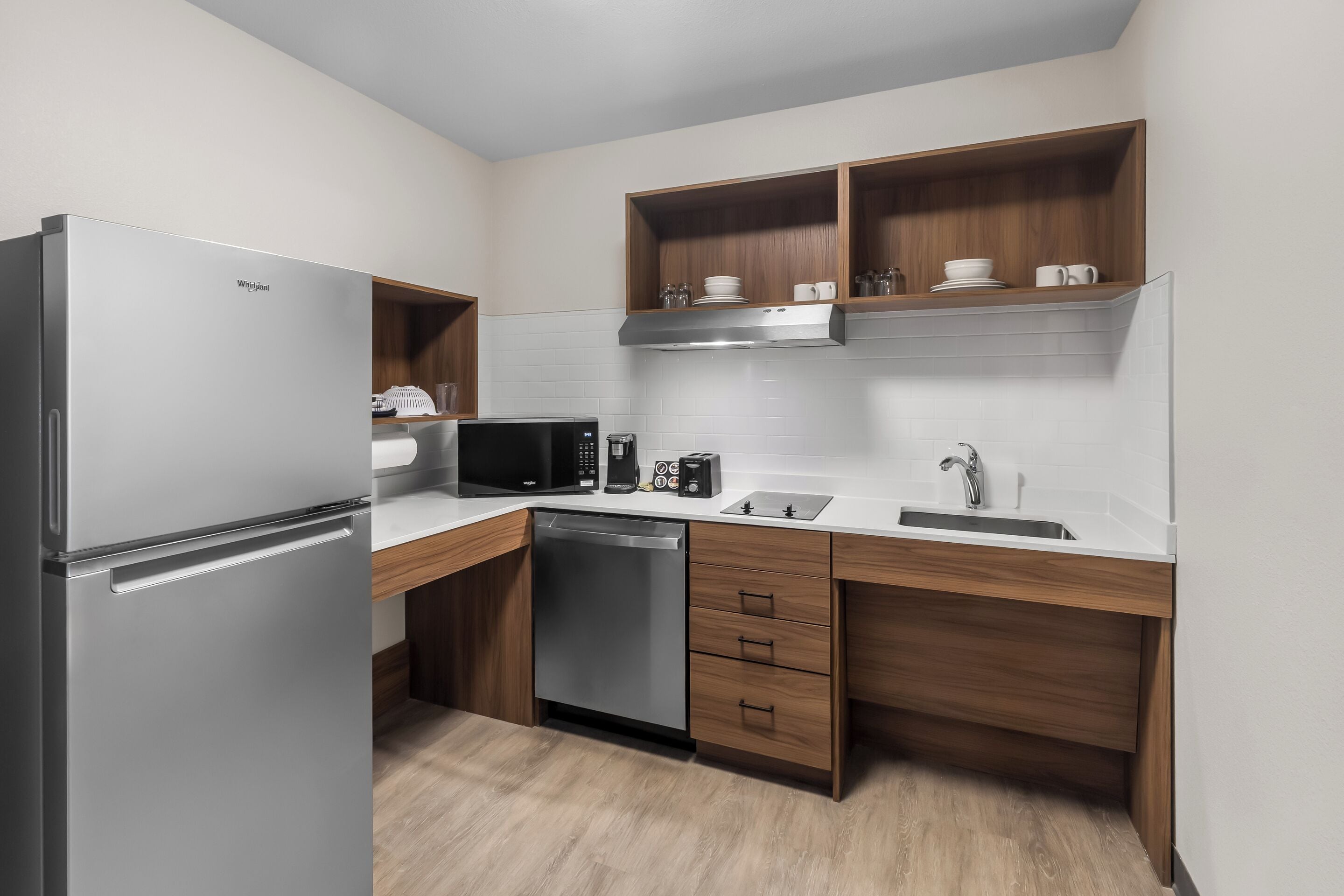 Una cocina compacta con refrigerador, microondas, cafetera y lavavajillas.