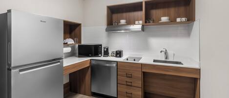 A compact kitchen with a refrigerator, microwave, coffee maker, and dishwasher.