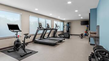Un gimnasio con cintas de correr, elípticas y mancuernas.