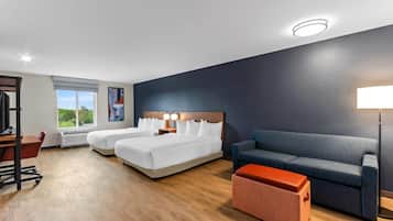 Habitación de hotel con dos camas, un sofá, un escritorio y una ventana con vistas.