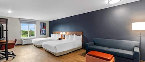 Une chambre d’hôtel avec deux lits, un canapé, un bureau et une fenêtre donnant sur un beau paysage.