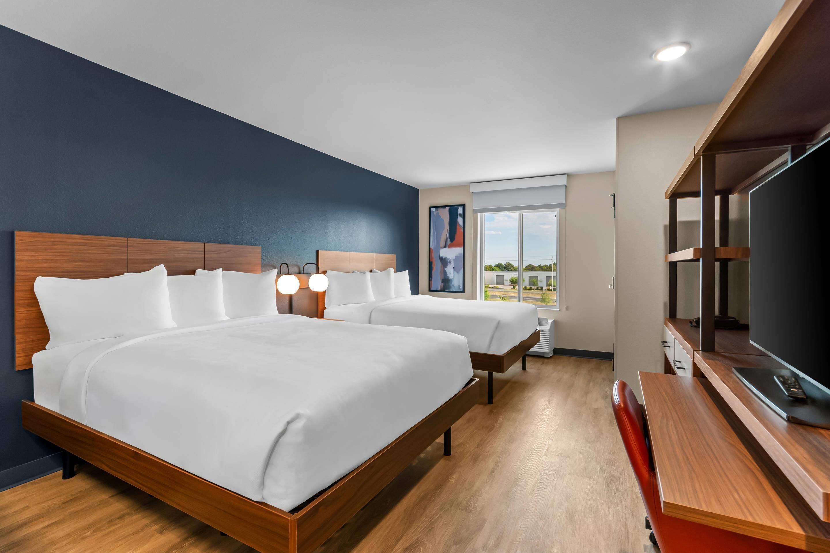 Une chambre d’hôtel avec un grand lit, un bureau avec une télévision et une fenêtre donnant sur un beau paysage.