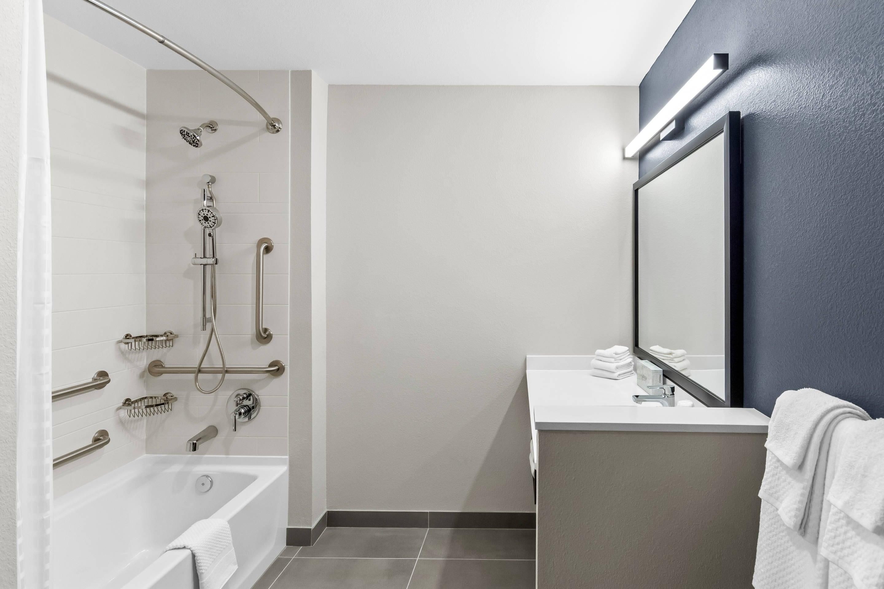 Un baño moderno con bañera, ducha y barras de apoyo.