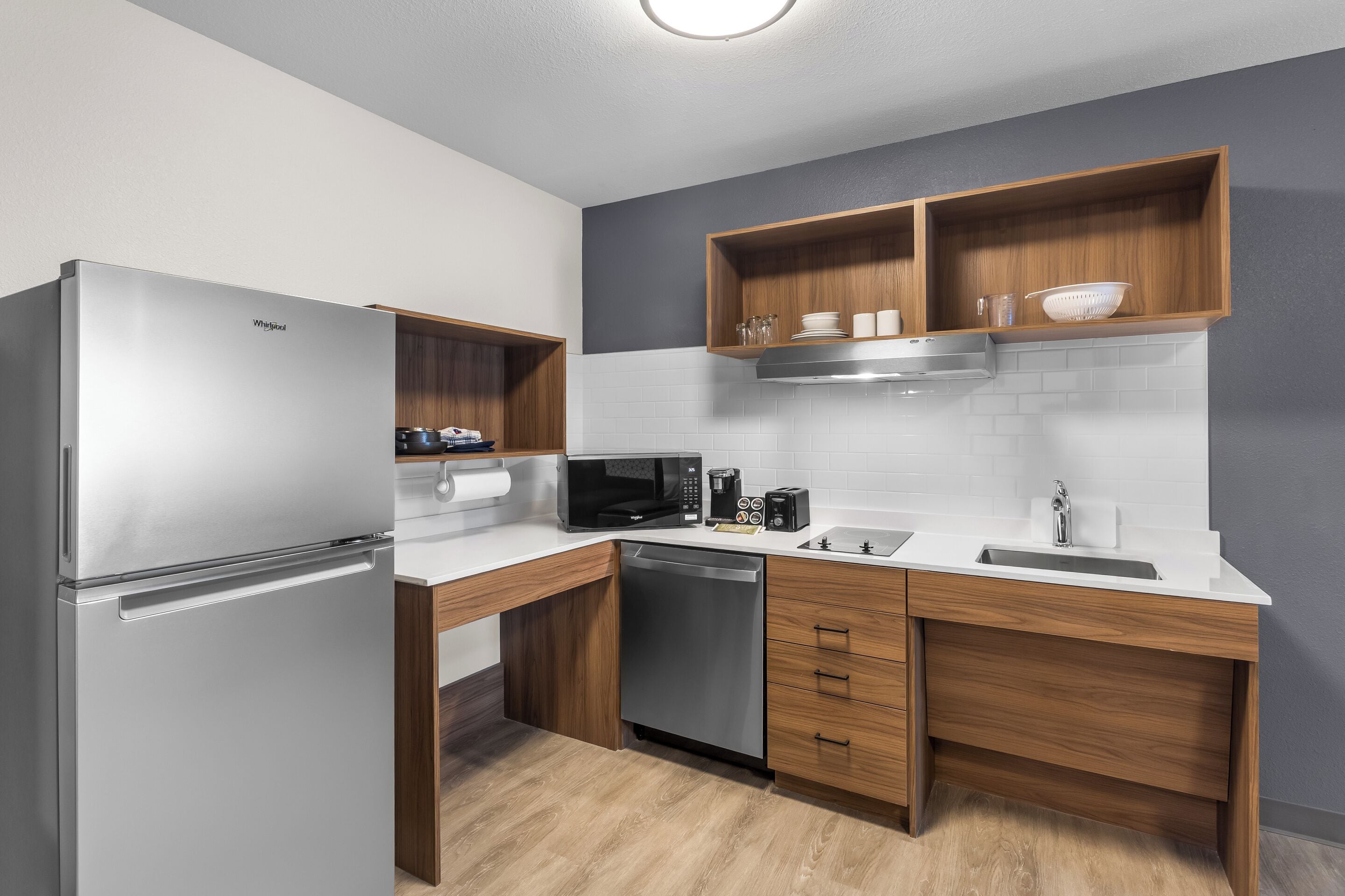 A modern kitchen with a stainless steel refrigerator, built-in microwave, and dishwasher.