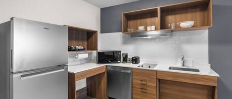 A modern kitchen with a stainless steel refrigerator, built-in microwave, and dishwasher.
