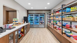 A clean, modern retail area with a wooden counter, refrigerated display cases, and shelves stocked with snacks and beverages.