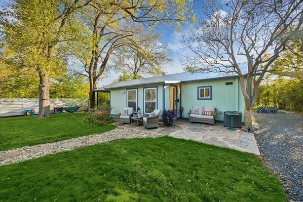 A house with a stone patio, outdoor seating, and a well-maintained lawn. - A Hoot’s Nest-Luxe 3 Bed Sleep-5 near Downtown ATX&UT COTA EV & COWBOYPOOL (Austin)