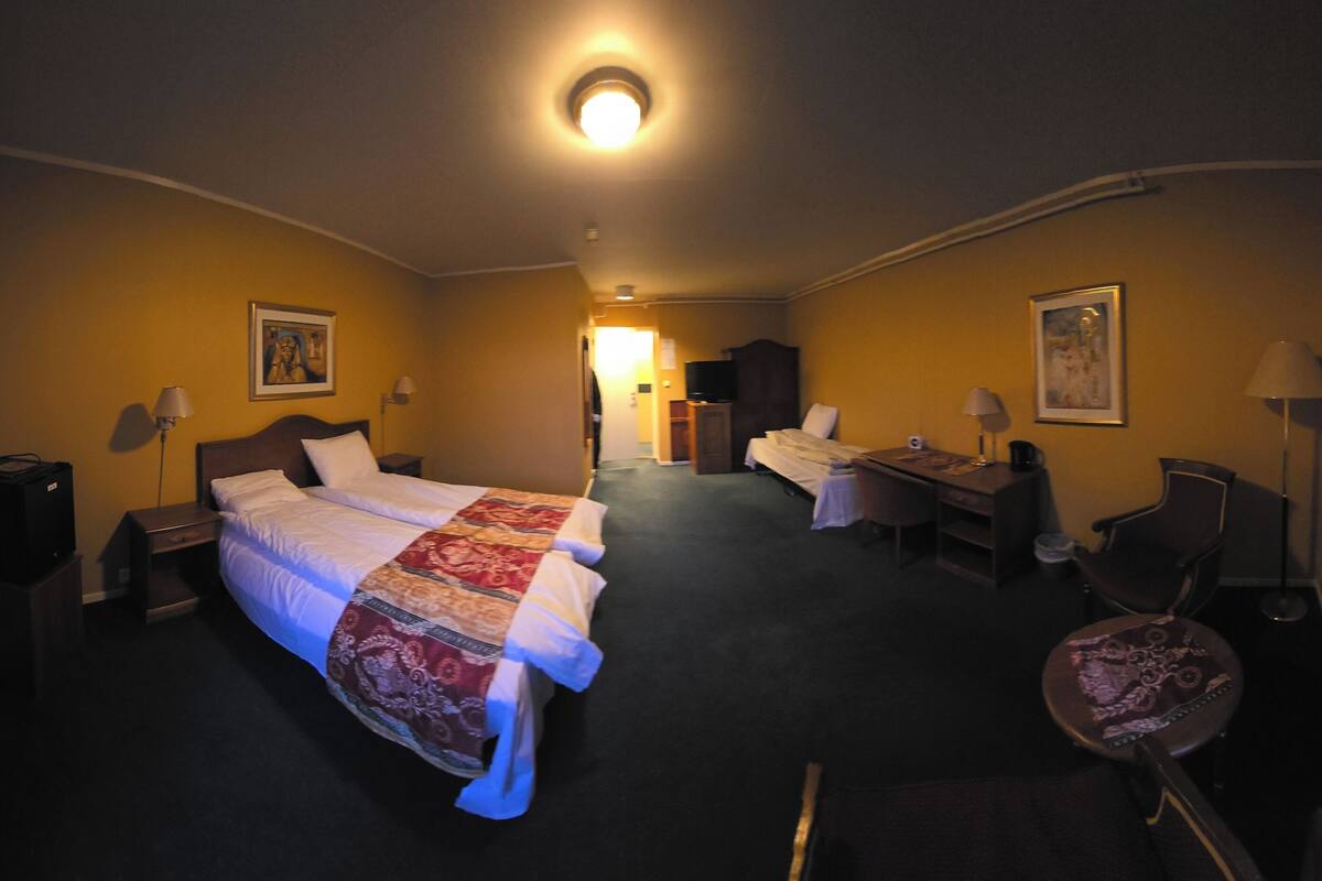 A hotel room with a bed, desk, chair, and a television.