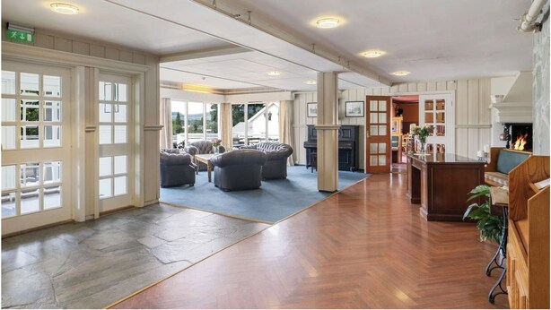 A spacious lobby with a wooden floor, a fireplace, and a seating area with sofas and armchairs. - Hotell Våler-Elverum-flisa-kirkenær (Våler)
