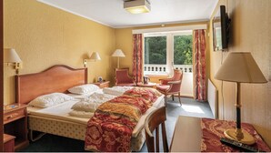 A hotel room with a bed, two chairs, a desk, a TV, and a window with curtains. - Hotell Våler-Elverum-flisa-kirkenær (Våler)