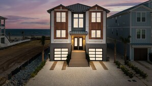 A modern two-story house with a large front porch, a garage, and a view of the ocean.