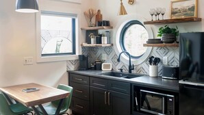 Uma cozinha moderna com mesa de madeira, cadeiras verdes, bancada preta e geladeira preta.