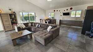 A spacious living area with a sectional sofa, a wooden coffee table, and a dining area with a kitchen in the background. - Villa with swimming pool for 6 people - Air conditioning, Wi-Fi, beach within walking distance (SOLARO)