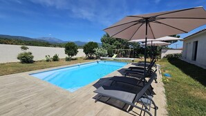 A swimming pool with lounge chairs and umbrellas, surrounded by a wooden deck and a grassy area. - Villa with swimming pool for 6 people - Air conditioning, Wi-Fi, beach within walking distance (SOLARO)