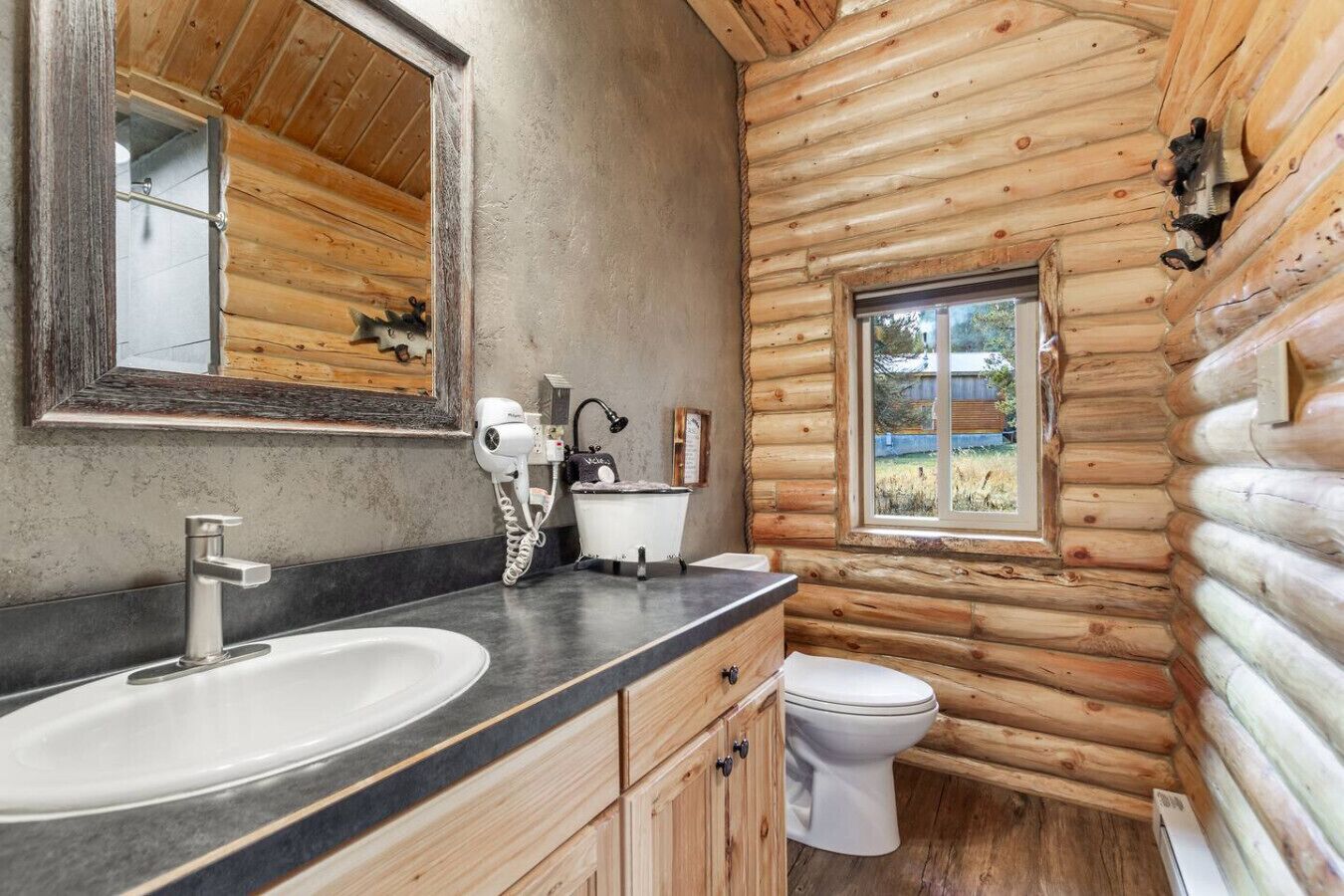 A log cabin bathroom with a sink, mirror, and toilet.