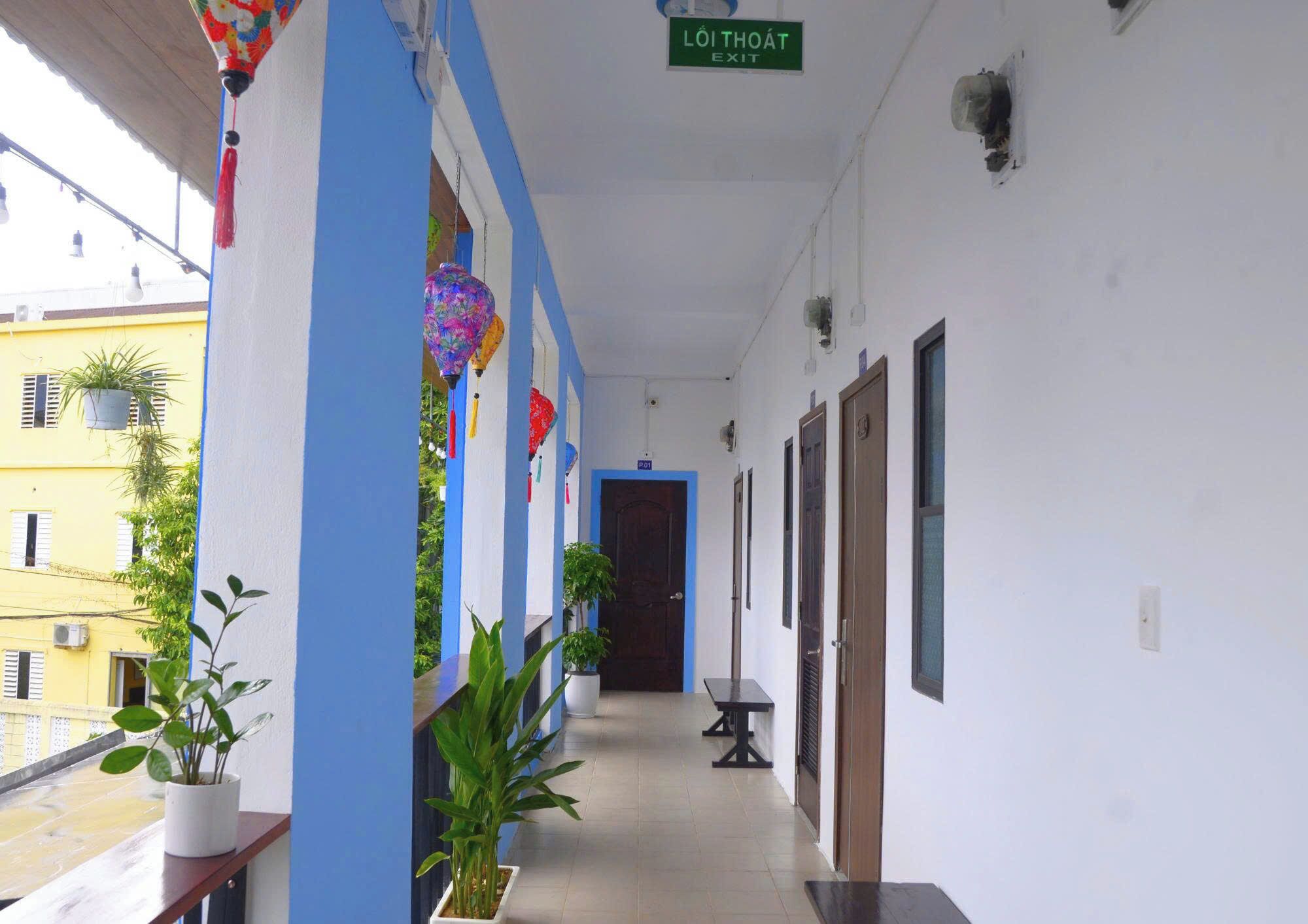 A corridor with a blue and white color scheme, potted plants, and a sign indicating an exit.