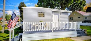 A single-story mobile home with a front porch, a small window, and a door. - Welcome to Bluebird Cottage (Lakeview)