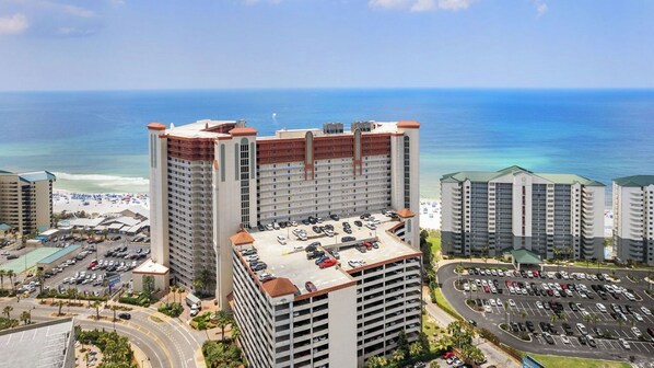 A high-rise hotel with multiple parking levels, a beach view, and a parking lot. - Beachfront Condo, Oceanview Balcony, Lagoon Pool Thomas Dr #2308 by Avantstay (Panama City Beach)