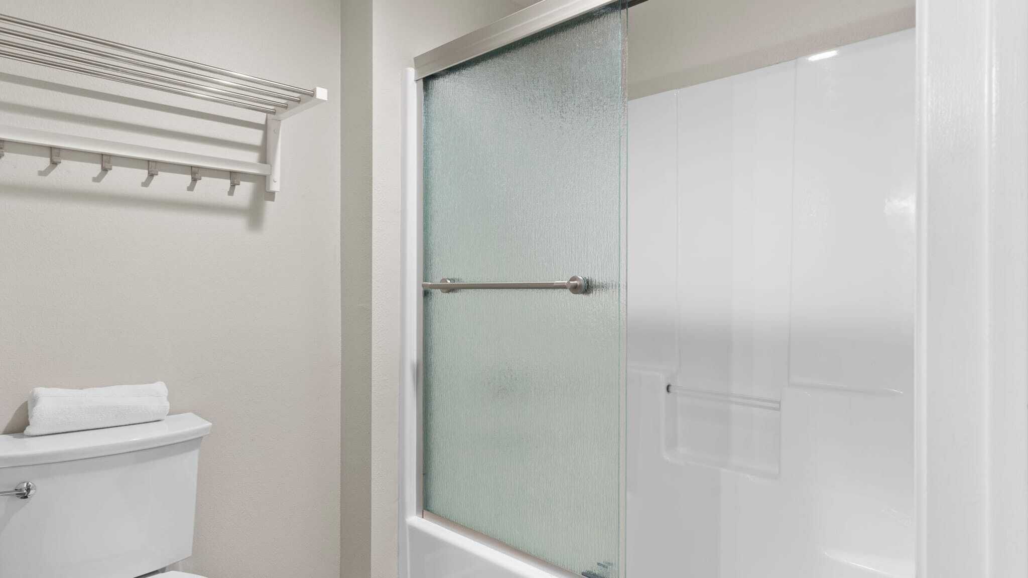 A bathroom with a toilet, a glass shower enclosure, and a towel rack.
