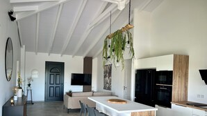 Una cocina moderna con una isla central, taburetes de bar y plantas colgantes.