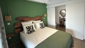 Un dormitorio con cama, paredes verdes, cabecero de madera y un espejo en la esquina.