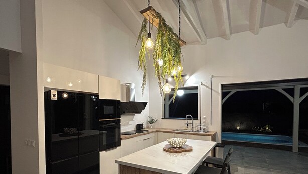 Una cocina moderna con electrodomésticos negros, una isla grande y una lámpara colgante.