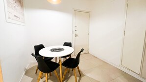 A dining area with a round table, four black chairs, a hanging pendant light, and a door in the background. - Rent Up - Estudio Moderno en Palermo (Buenos Aires)