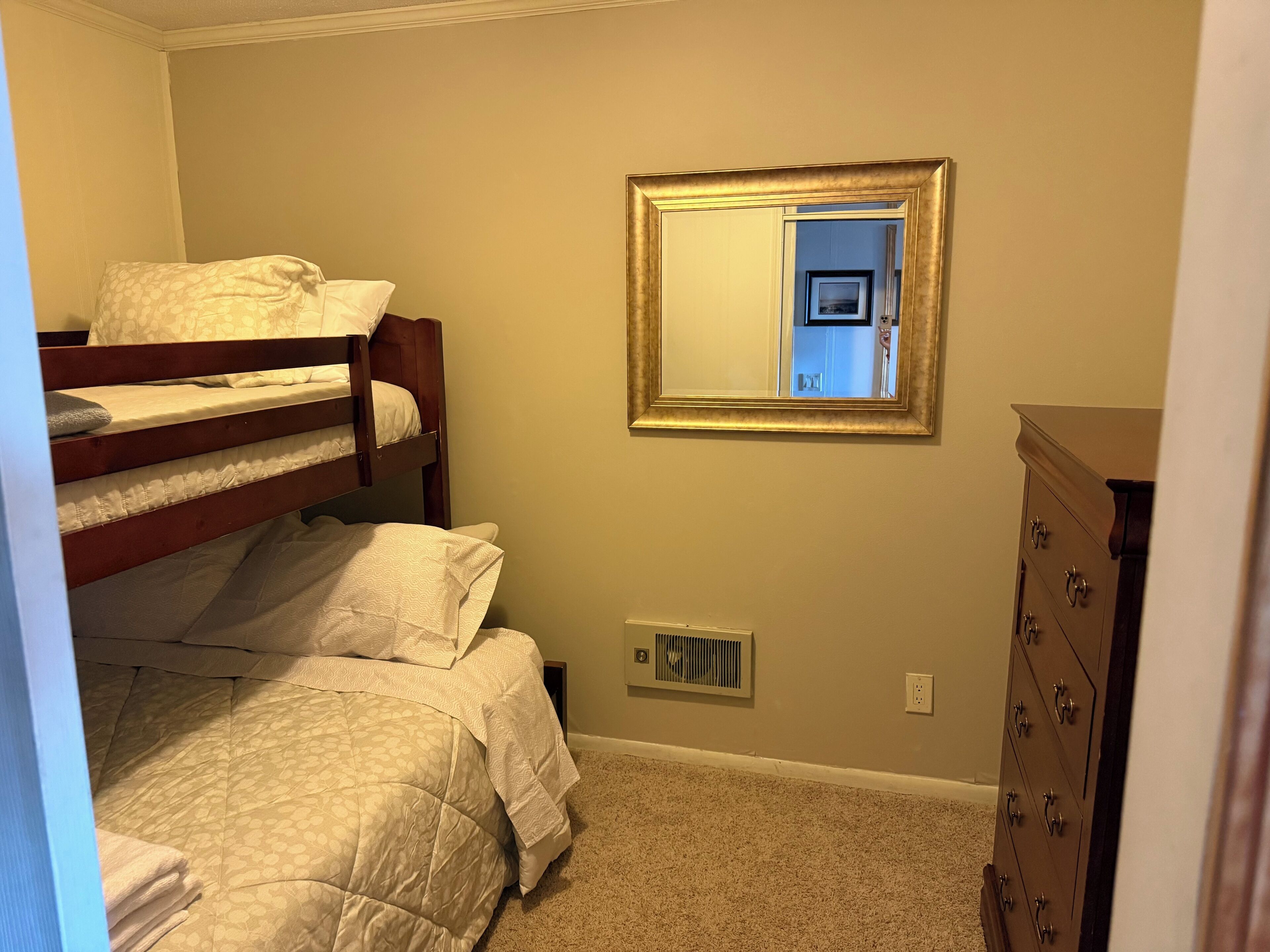 Una camera da letto con letti a castello, una cassettiera e uno specchio appeso al muro.