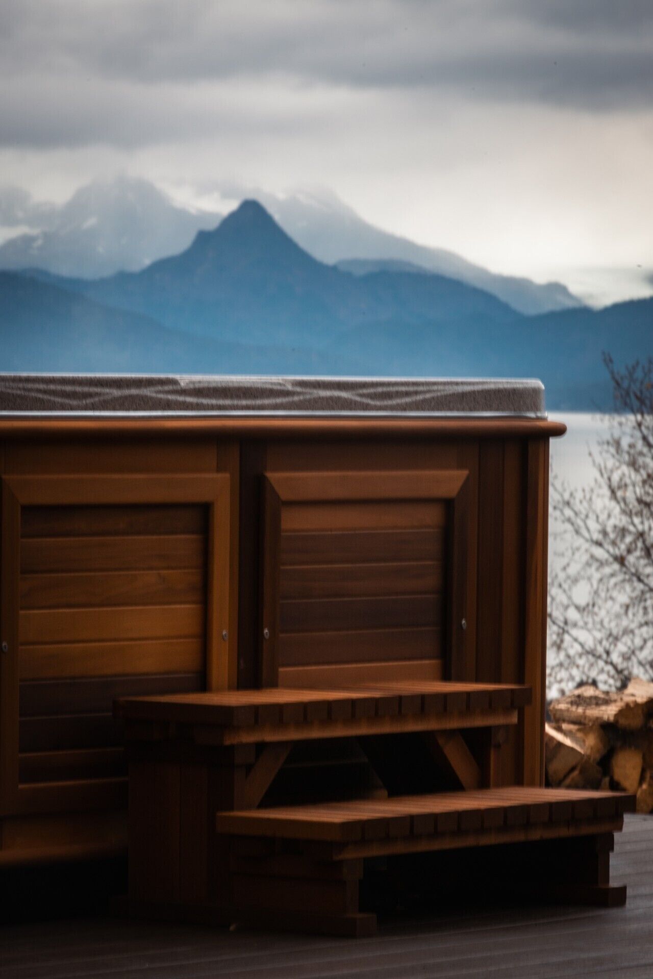A wooden hot tub with a view of mountains in the background.