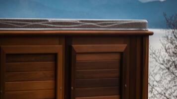A wooden hot tub with a view of mountains in the background.