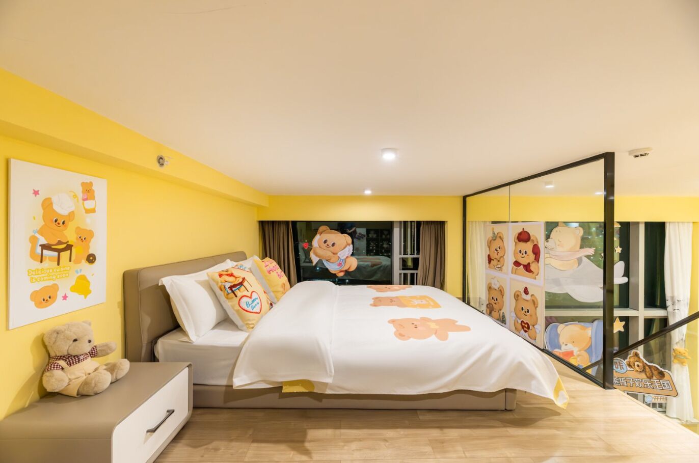 Ein Schlafzimmer mit Bett, Kissen, einem Nachttisch, einem Teddybären und einem Fenster mit Vorhängen.