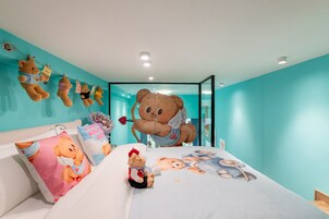 Un dormitorio con una cama grande, un oso de peluche en la cama y varios osos de peluche colgados en la pared.