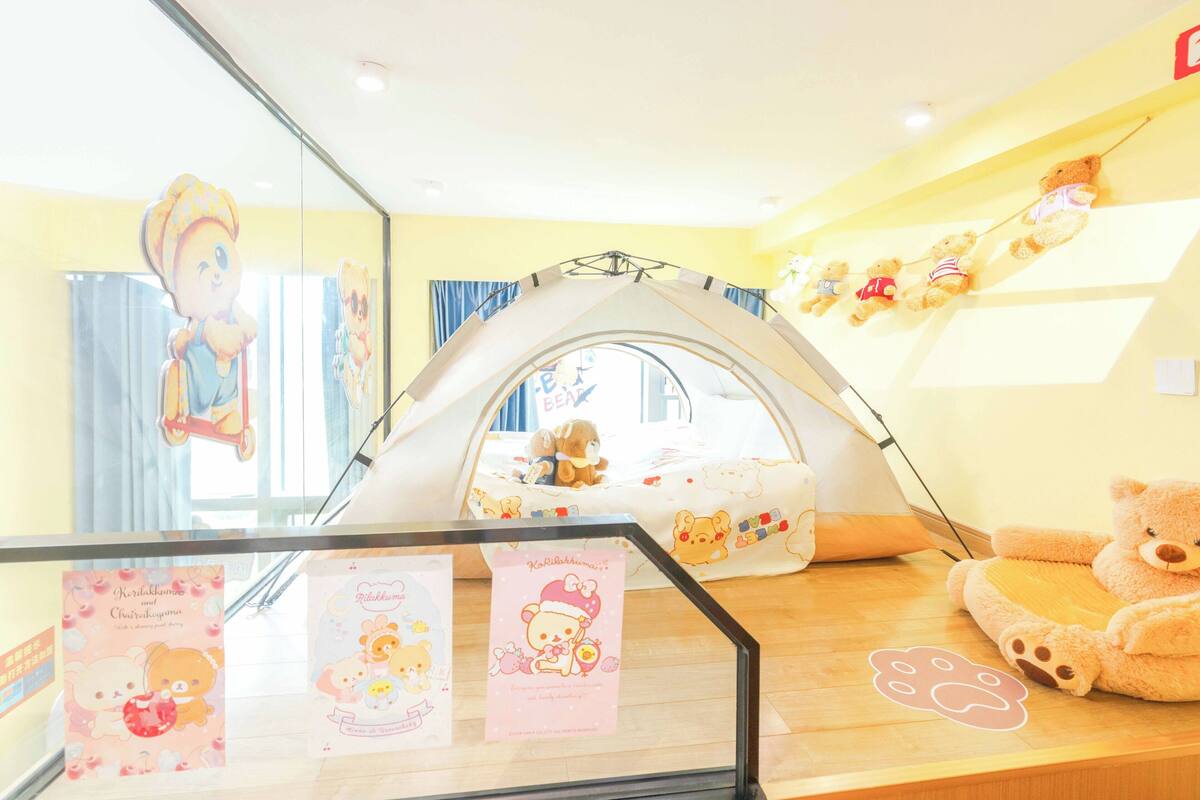 Une pièce avec une structure ressemblant à une tente, un ours en peluche et des livres pour enfants sur la table.